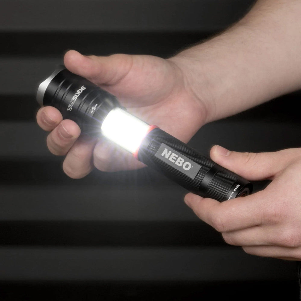 Flashlight labeled ’NEBO’ being held and illuminated in someone’s hand.