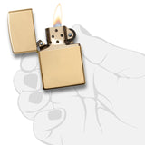 Gold-colored metal lighter with an open lid and visible flame.