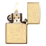 Gold-colored Zippo lighter with an ornate floral engraving pattern, shown lit with a flame.