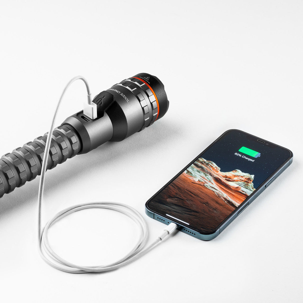 Handheld device with a cylindrical body and multiple colored rings, connected by a cable to a smartphone.