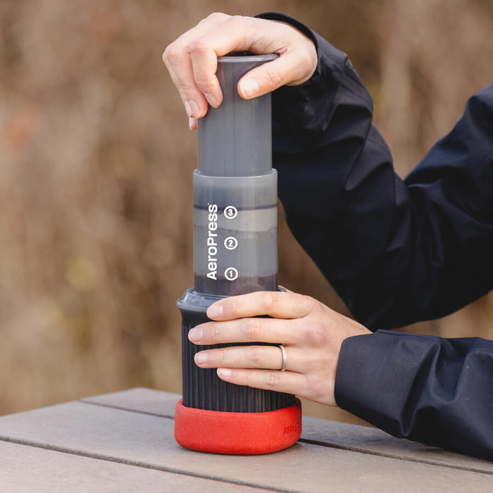 Portable coffee maker or espresso machine with a gray body and red base.